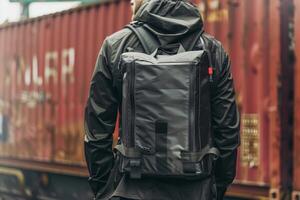 Man with a black backpack is standing near the railway photo