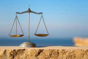 Balancing scale of justice standing on stone with sea in background photo