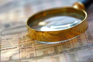 Magnifying glass analyzing financial spreadsheet data close up photo