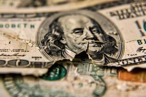 Torn one hundred dollar bill lying on other bills photo