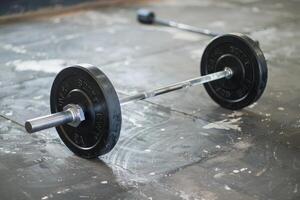 Barbell with weights resting on gym floor after intense workout session photo