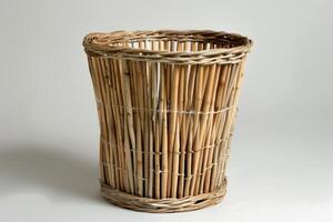 Empty wicker trash can standing on white background photo