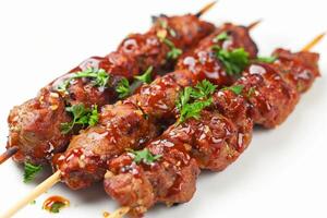 Grilled meat skewers with sauce and herbs on white plate photo