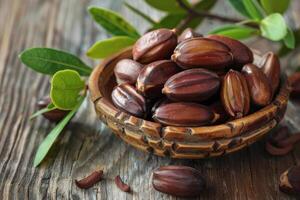 Argan nuts in wooden bowl with branch on rustic table photo