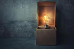 Glowing light bulb illuminating cardboard box on dark background photo