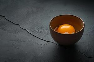 Egg yolk inside small ceramic bowl on dark background photo