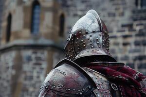 Medieval knight wearing helmet and armor in front of stone building photo