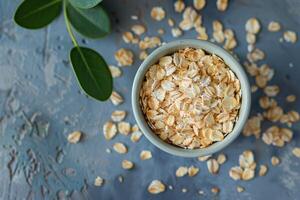 Rolled oats in a bowl with green leaves on rustic background photo