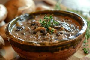 Creamy mushroom soup garnished with fresh thyme in rustic bowl photo