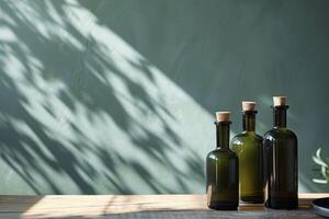Three green glass bottles with cork lids on wooden table with leaf shadow background photo