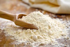Wooden spoon scooping fine white flour on rustic table photo