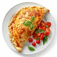 Delicious closed pizza calzone with tomato and basil on white plate photo