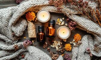 Three bottles of essential oils are on a table with a blanket and candles photo