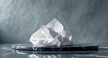 Crumpled white tissue on glossy marble surface with soft grey textured wall background creating ample negative space for text and design photo