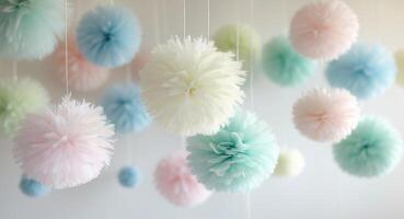 Pastel colored paper pom poms hanging from strings creating a party decoration. photo