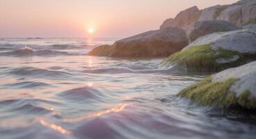 tranquilo costero escena con rocas y fluido agua a puesta de sol con suave pastel colores foto