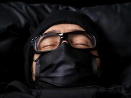 Close up of a person sleeping while wearing a black face mask and glasses photo