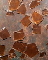 Broken amber glass pieces on a rusty surface photo