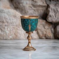 Ornate golden chalice with teal inlay on marble surface photo