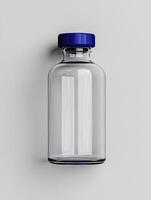 Empty glass bottle with a blue cap on a white background photo