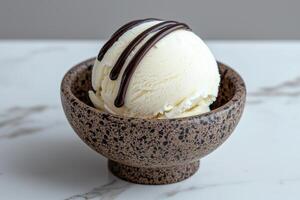 A scoop of vanilla ice cream with chocolate syrup in a small bowl photo