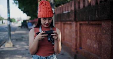 Handheld selective focus shot, Happy woman standing looking at photos from her camera on a sidewalk in the city. Enjoy the moments during journey video