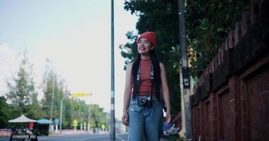 Handheld low angle view shot, Happy Asian woman smiles while enjoying a walk along the street on a sunny day. Enjoy the moments during journey video