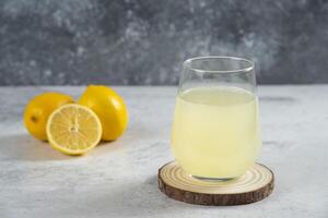 a glass of lemonade with a slice of lemon on a wooden coaster photo