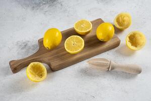 wooden cutting board with lemons and a wooden spoon photo