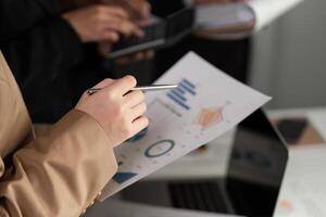 Businessman Analyzing Stock Graphs on Laptop and Paper Charts in Modern Office Setting for Financial and Investment Insights photo