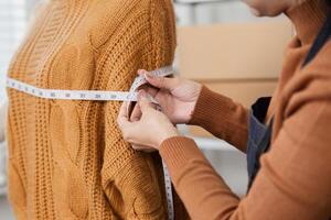 Female tailor taking measurements of a sweater on a mannequin, focusing on accuracy in a fashion workshop photo