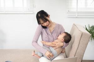 Single mom balancing work and parenting while discussing tasks on the phone with her baby in her lap photo