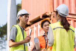 Logistics engineering team strategizing project details at a construction site with blueprints and tools photo