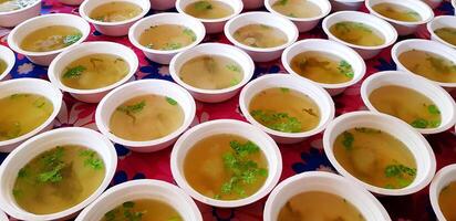 Many hot soup with boiled green squash and coriander in white foam bowl for table. Group of food for lunch. photo