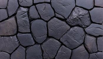 Close-up view of dark, irregular stones arranged in a unique pattern for wall design photo