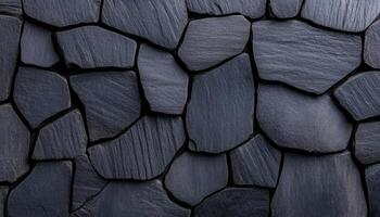 Dark slate stones of different sizes are arranged closely to form a textured wall surface photo