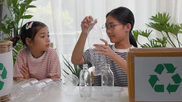 Asian siblings recycle household waste Protect nature, and save the environment. children learn to sort garbage by putting plastic bottles in the recycle photo