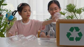 Asian siblings recycle household waste Protect nature and save the environment. children learn to sort garbage by putting plastic bottles in the recycle photo