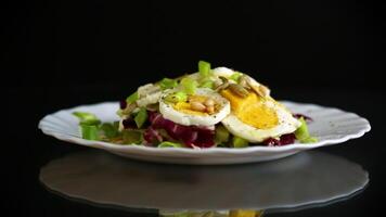 Salad with seeds and vegetables in a plate, isolated on a black background video