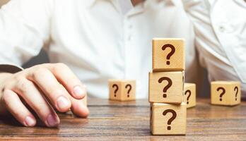 Man is in thought and blocks with questions. Pondering the problem, gathering all the facts. Make the right decision. Reasoning, weighing results and consequences. Reflection and planning. Strategy. photo