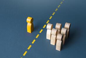 A person and a group of people are separated by a yellow line. Establishing contact. Distrust. Quarantine. Distance with strangers. Barrier to understanding, difficult integration. Rejection, refusal. photo