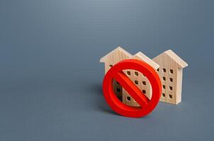 Residential buildings and red prohibition symbol No. Restrictions ban on construction. Inaccessible expensive housing. Restriction building compaction. Underdeveloped infrastructure utilities photo