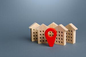 Wooden houses and a red location pin. Location, accessibility and proximity to infrastructure. Residential complex. City navigation, orienteering. Visit the town. Search for housing options photo