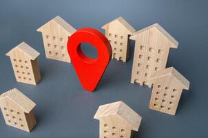 Wooden houses and a red location pin. Location, accessibility to infrastructure. Residential complex. Navigation and orientation within city. Business advertising. Tracking. Moving to different city photo