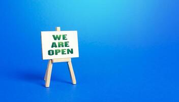 We Are Open easel sign. Exit from severe quarantine conditions, economic and business recovery. Return to normal life. Adaptation to rules. Business flexibility and readiness for new challenges. photo