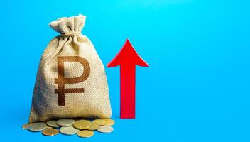 russian ruble money bag with red arrow up. Raising taxes. Deposit interest. Increase in profitability and prosperity, higher living standards. Recover financial system after crisis. Budget growth. photo