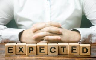 Folded hands on a background of word Expected. Foresight and foresight concept. Be prepared for any possible situation. Planning and solution development. Confidence. Expectability. Case scenario photo