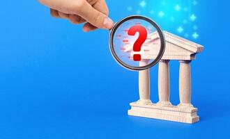 A hand with a magnifying glass inspects bank and finds financial violations. Audit and accounting. photo