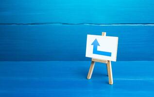 Easel with a blue left arrow. Minimalism. Direction to go around on the left. Advertising. Navigation, customer acquisition. Obscure obstacles, move towards the goal. New rules. Copy space photo