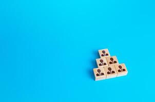 Wooden block people pyramid. Structure of organization, vertical of company power. Grouping, distribution of positions and responsibilities. Recruiting and hiring candidates, team building. photo